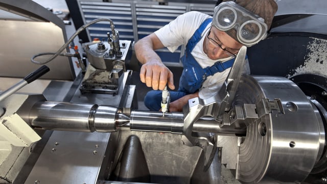 Arbeiter fräst an einem Metallteil auf einer Drehbank Arbeiter fräst an einem Metallteil auf einer Drehbank