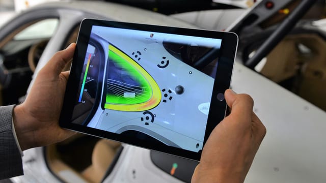 Ein Tablet scant die Oberfläche eines Autos und färbt Bereiche grün ein. Ein Tablet scant die Oberfläche eines Autos und färbt Bereiche grün ein.