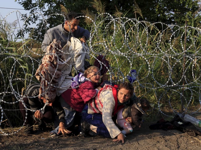 Syrische Flüchtlinge im Sommer 2015 bei einem Zaun an der serbisch-ungarischen Grenze. Syrische Flüchtlinge im Sommer 2015 bei einem Zaun an der serbisch-ungarischen Grenze.