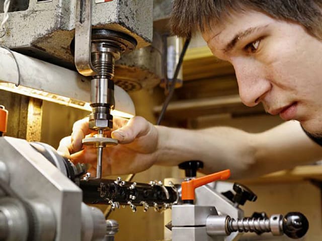 Mit einer Bohrmaschine bearbeitet der Blasinstrumentenbauer eine Oboe.