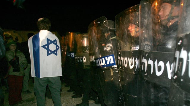 Ein Siedler im Westjordanland vor Polizeikräften. Ein Siedler im Westjordanland vor Polizeikräften.