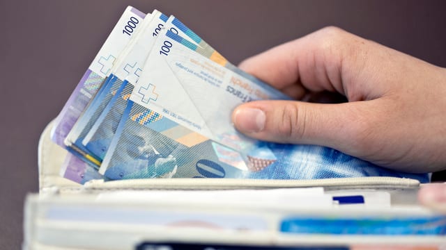 Geldscheine werden in ein Portemonnaie gelegt Geldscheine werden in ein Portemonnaie gelegt