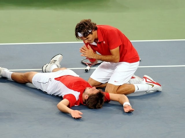 Roger Federer wärmt symbolisch seine Hände am brennenden Stan Wawrinka. Roger Federer wärmt symbolisch seine Hände am brennenden Stan Wawrinka.