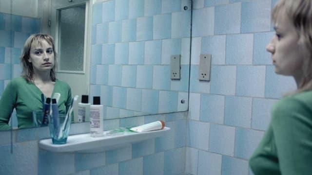 Eine Frau steht im Badezimmer und schaut sich im Spiegel an. Eine Frau steht im Badezimmer und schaut sich im Spiegel an.