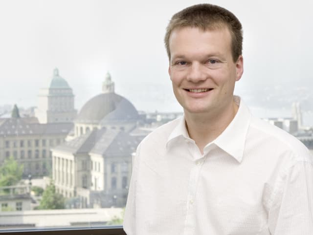 Porträt von Reto Knutti, auf seinem Schoss ein Laptop, im Hintergrund das Gebäude der ETH Porträt von Reto Knutti, auf seinem Schoss ein Laptop, im Hintergrund das Gebäude der ETH
