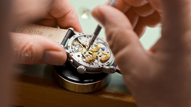 Ein Uhrmacher arbeitet an einem Uhrwerk.