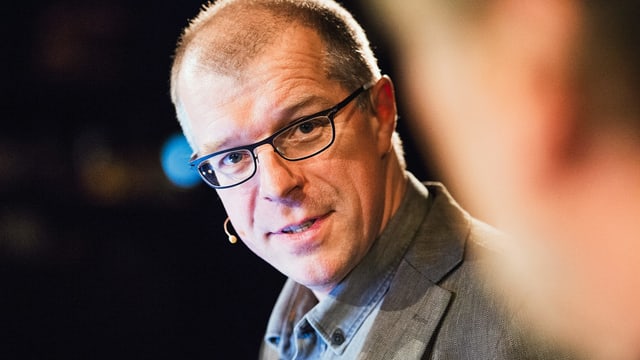 Ein Mann mit Brille und Mikrofon. Ein Mann mit Brille und Mikrofon.