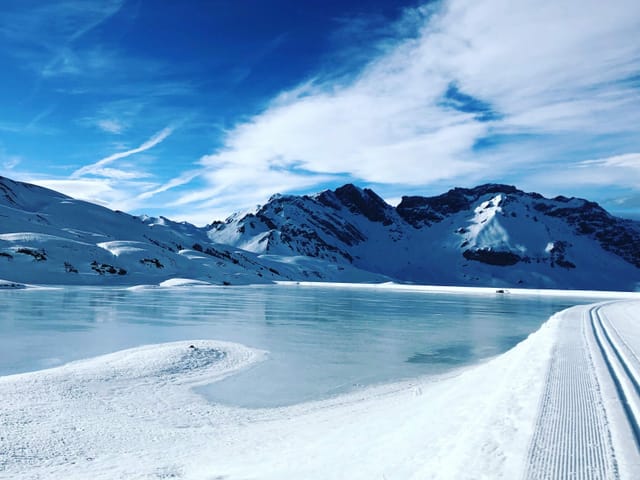 Schneelandschaft mit Bergen und einem See im Vordergrund