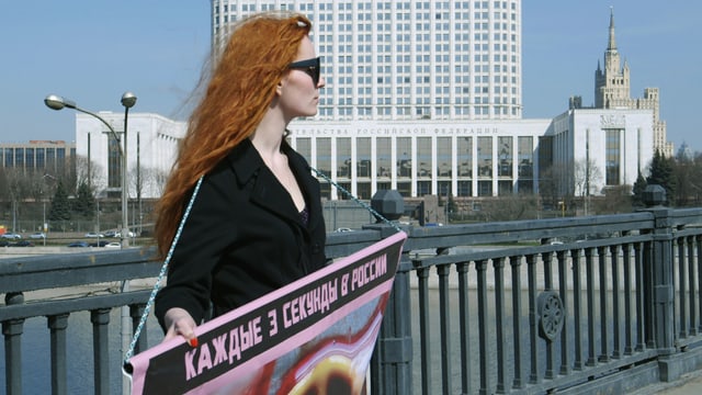 Natalia steht auf der Brücke mit einem Plakat. Natalia steht auf der Brücke mit einem Plakat.