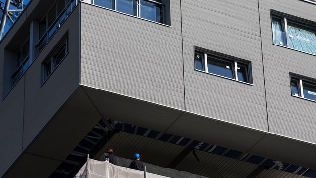 Bauarbeiter auf dem Dach des Silos geben Anweisungen, damit das Haus genau an der richtigen Stelle platziert wird. Bauarbeiter auf dem Dach des Silos geben Anweisungen, damit das Haus genau an der richtigen Stelle platziert wird.