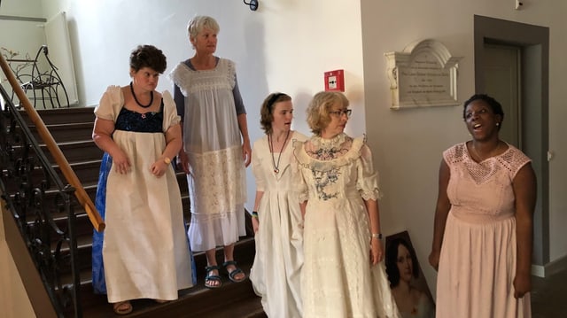 Fünf Frauen in langen Gewändern stehen in einem Treppenhaus. Fünf Frauen in langen Gewändern stehen in einem Treppenhaus.