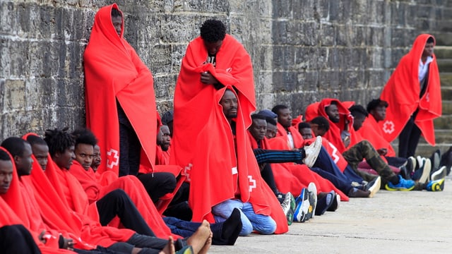 In Decken gehüllte Flüchtlinge In Decken gehüllte Flüchtlinge
