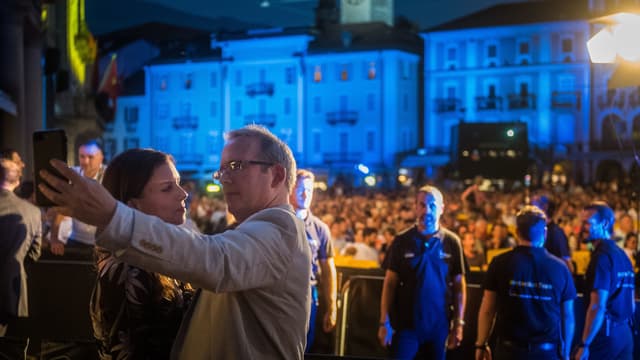 Ein Mann und eine Frau machen zusammen ein Selfie vor dem Publikum auf der Piazza Grande. Ein Mann und eine Frau machen zusammen ein Selfie vor dem Publikum auf der Piazza Grande.