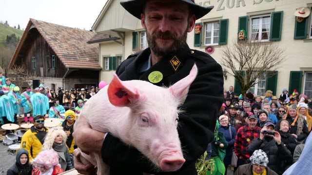Ein Mann mit einem Schwein auf den Armen. Ein Mann mit einem Schwein auf den Armen.