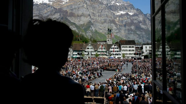 Frau schaut aus dem Fenster auf die Landsgemeinde. Frau schaut aus dem Fenster auf die Landsgemeinde.