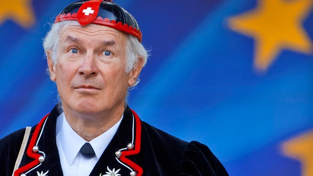 Ein Mann in typischer Schweizer Volkstracht vor der EU-Flagge. Ein Mann in typischer Schweizer Volkstracht vor der EU-Flagge.