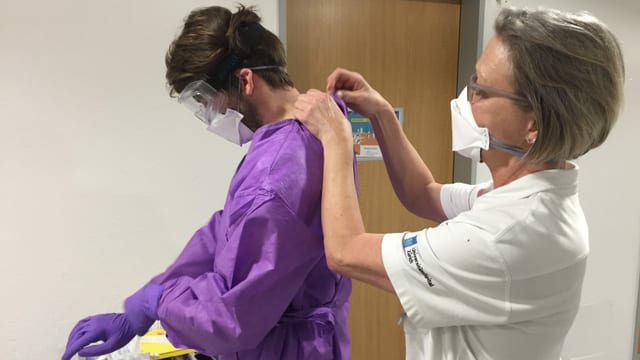 Ein Assistenzarzt wird mit spezieller Schutzkleidung ausgerüstet. Ein Assistenzarzt wird mit spezieller Schutzkleidung ausgerüstet.