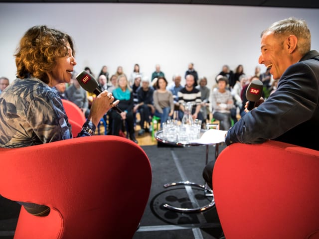 Zwei Menschen sitzen auf Stühlen und beantworten Fragen