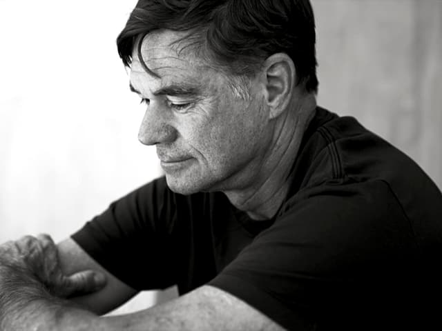 Gus van Sant, in schwarzem Shirt, sitzend, auf den Boden schauend. Gus van Sant, in schwarzem Shirt, sitzend, auf den Boden schauend.