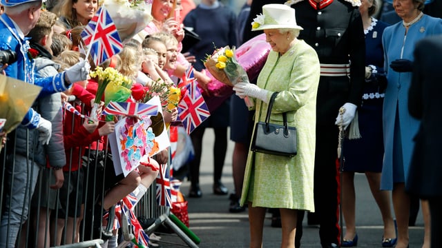 .Die QUeen in einen gelben Matel mit passendem Hut. Sie nmmt Blumen aus der feiernden Menge entgegen .Die QUeen in einen gelben Matel mit passendem Hut. Sie nmmt Blumen aus der feiernden Menge entgegen