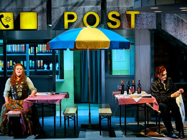 Mann und Frau sitzen auf Bänken vor der Post. Mann und Frau sitzen auf Bänken vor der Post.