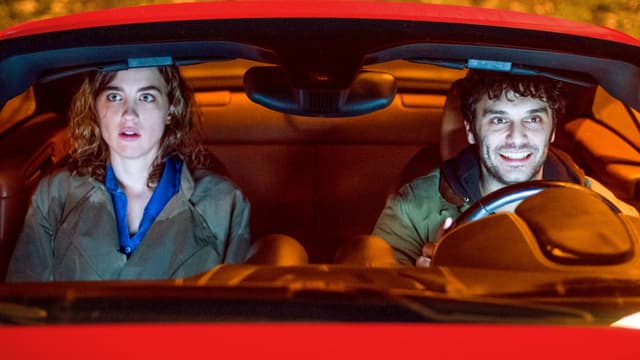 Mann und Frau in einem roten Auto Mann und Frau in einem roten Auto