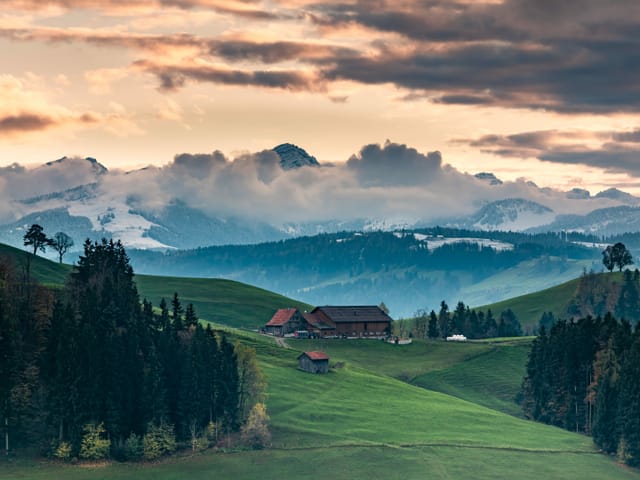 Grüne Hügel und Schneeberge mit Wolken im Hintergrund