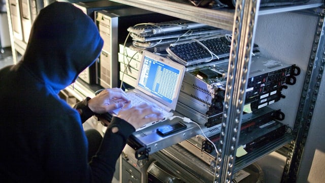 Person mit Hoodie an einem Laptop Person mit Hoodie an einem Laptop