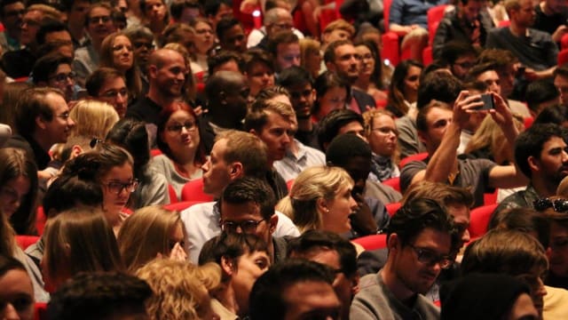 Leute sitzen in einem Saal. Leute sitzen in einem Saal.