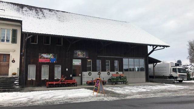 Blick auf ein Bauernhaus mit Reklametafel am Strassenrand Blick auf ein Bauernhaus mit Reklametafel am Strassenrand