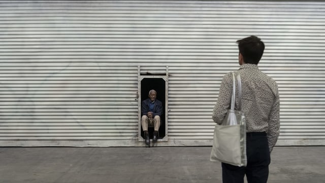 Man steht vor Mann, der in einem Türrahmen sitzt. Man steht vor Mann, der in einem Türrahmen sitzt.