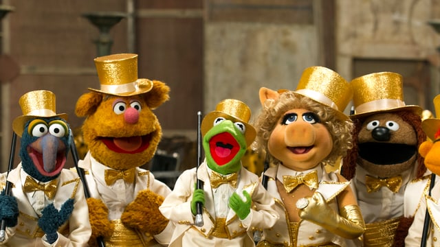Fünf Muppet-Puppen mit Anzügen und goldenen Hüten