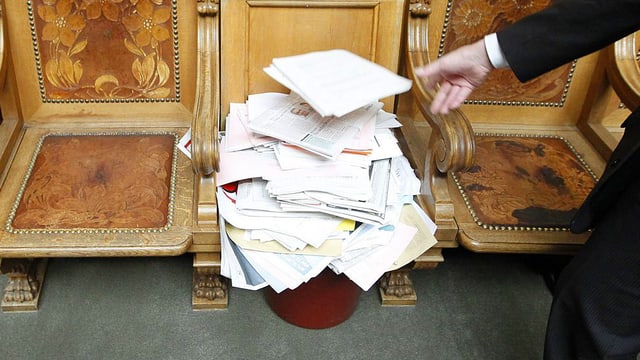 Jemand wirft Papier in einen Abfalleimer im Nationalratssaal Jemand wirft Papier in einen Abfalleimer im Nationalratssaal
