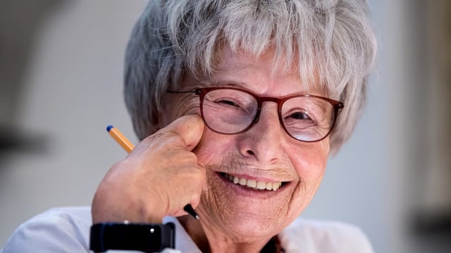 Eine Frau mit grauem Haar, Brille und einem Stift in der Hand. Eine Frau mit grauem Haar, Brille und einem Stift in der Hand.