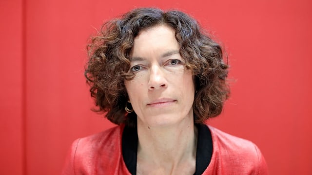 Porträtaufnahme einer Frau mit dunklen Haaren vor einem roten Hintergrund Porträtaufnahme einer Frau mit dunklen Haaren vor einem roten Hintergrund