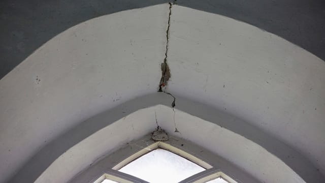 Ein Kirchenfenster mit grossen Rissen in der Decke. Ein Kirchenfenster mit grossen Rissen in der Decke.