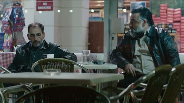 Stratos sitzt zusammen mit dem Gangsterboss ausserhalb eines Restaurants. Stratos sitzt zusammen mit dem Gangsterboss ausserhalb eines Restaurants.