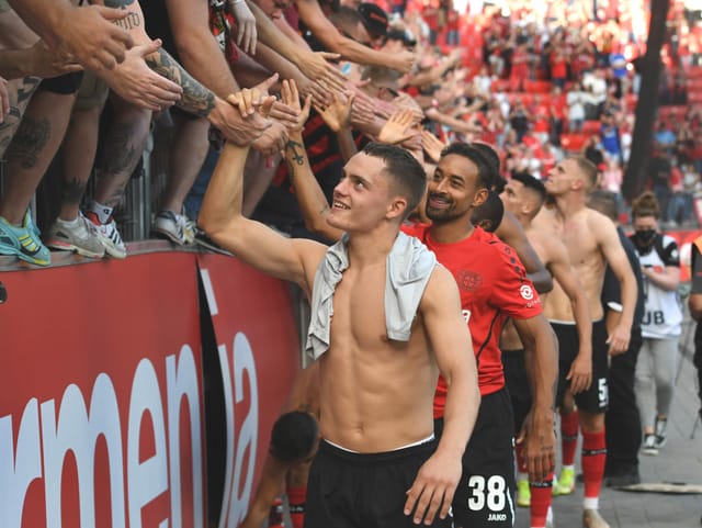 Leverkusens Florian Wirtz klatscht nach Spielschluss mit den Fans im Stadion ab.