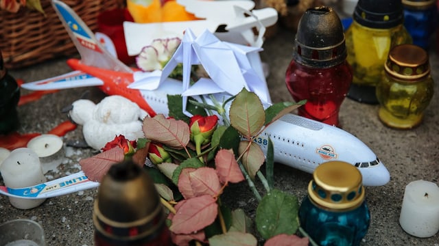 Blumen zum Gedenken an Opfer und ein Plastikflugzeug.
