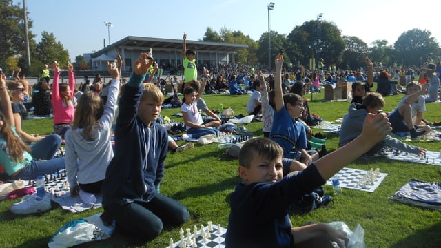 Kinder sitzen am Boden und strecken einen Arm in die Höhe, als wollten sie sich im Unterricht melden. Kinder sitzen am Boden und strecken einen Arm in die Höhe, als wollten sie sich im Unterricht melden.
