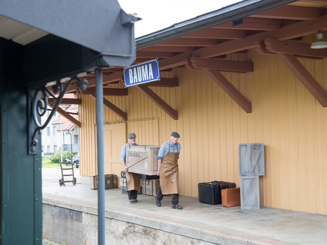 Zwei Männer tragen Holzkiste am Bahnhof Bauma Zwei Männer tragen Holzkiste am Bahnhof Bauma