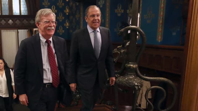 John Bolton und Sergei Lavrov gehen über einen Teppich John Bolton und Sergei Lavrov gehen über einen Teppich