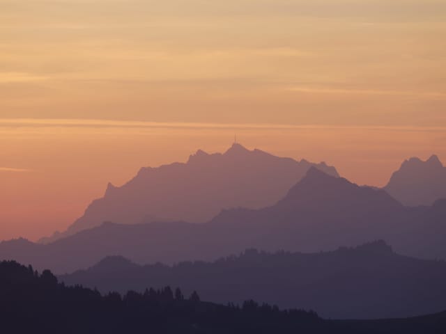 Verschieden beleuchtete Hügel- oder Gebirgsketten in der Morgendämmerung.