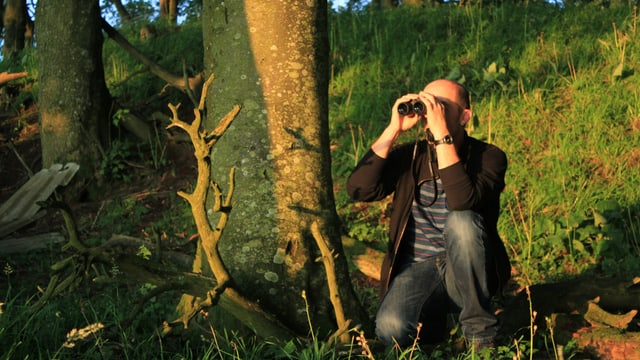 Andrew Bond mit Feldstecher im Wald Andrew Bond mit Feldstecher im Wald