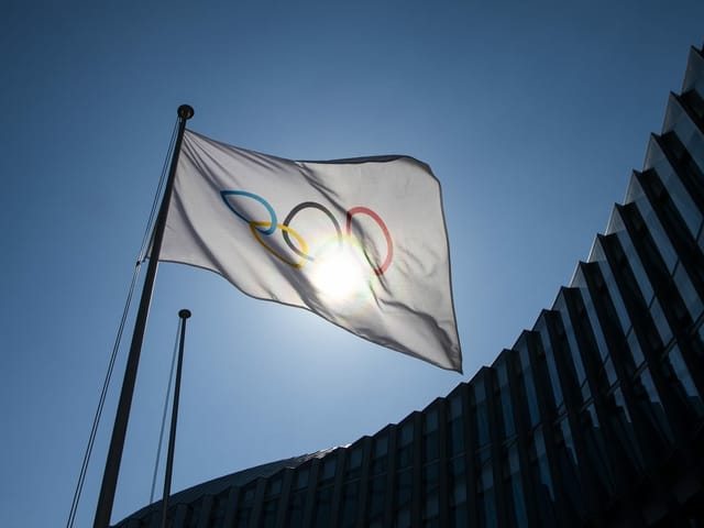 Olympische Flagge vor der Sonne im Winde wehend Olympische Flagge vor der Sonne im Winde wehend