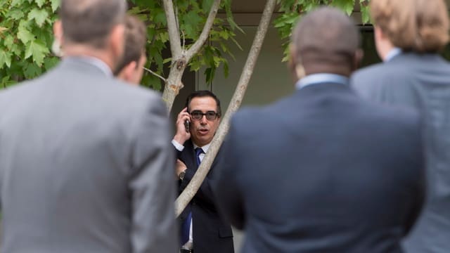 US-Finanzminister Steven Mnuchin am Telefon, umringt von Sicherheitskräften. US-Finanzminister Steven Mnuchin am Telefon, umringt von Sicherheitskräften.