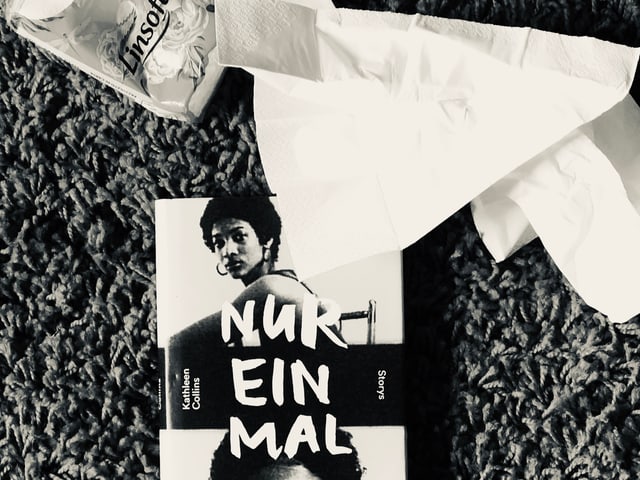 Der Erzählband von Kathleen Collins: «Nur einmal» liegt auf einem Teppich, zerknüllte Nastücher daneben Der Erzählband von Kathleen Collins: «Nur einmal» liegt auf einem Teppich, zerknüllte Nastücher daneben