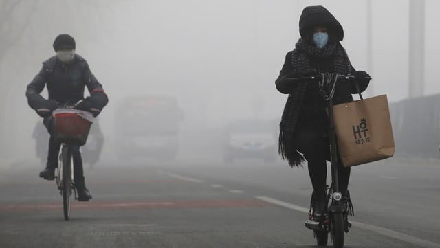 Velofahrer in Peking mit einer Schutzmaske. Velofahrer in Peking mit einer Schutzmaske.