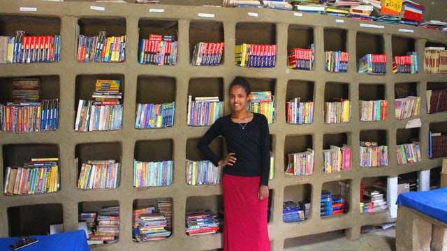 Eine Frau steht vor einer Bücherwand Eine Frau steht vor einer Bücherwand