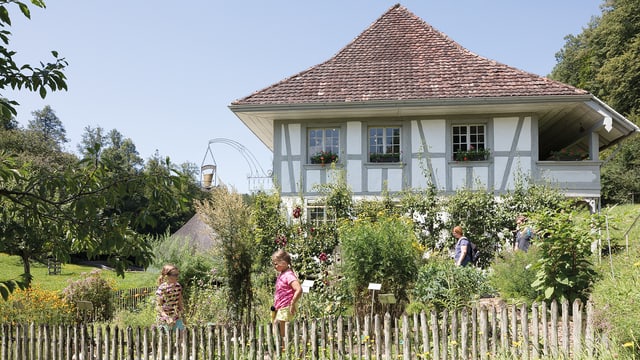 Zwei Kinder in einem Garten vor einem traditionellen Haus. Zwei Kinder in einem Garten vor einem traditionellen Haus.